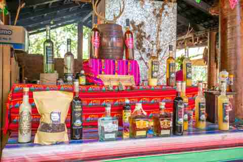 Barra colorida con botellas de licores artesanales y artesanías mexicanas