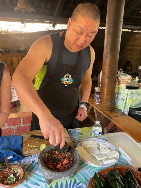 Participante moliendo salsa en molcajete durante la clase de cocina