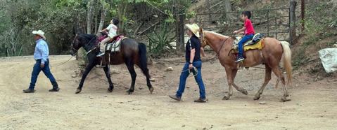 Guías llevando a niños a caballo por el picadero